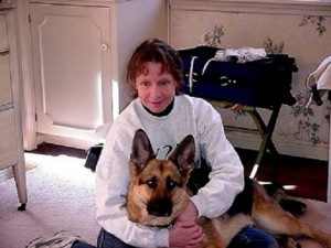 Sue sitting on the floor with her Seeing Eye dog sprawled across her lap.